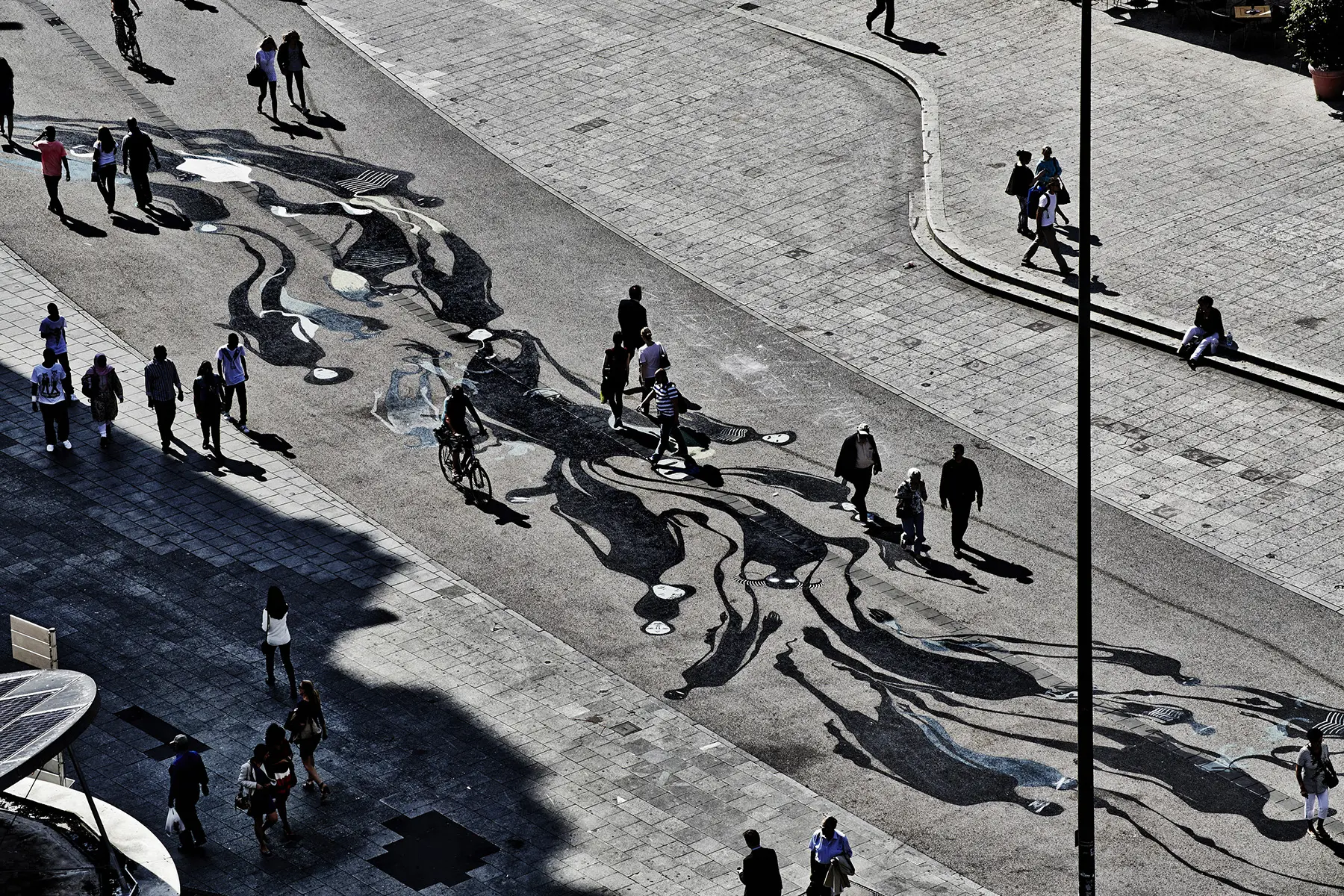 Aerial view of a city square with long human shadows